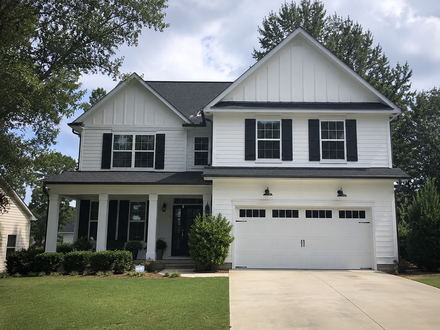 Custom-build two-story farmhouse exterior with black shutters in Mauldin